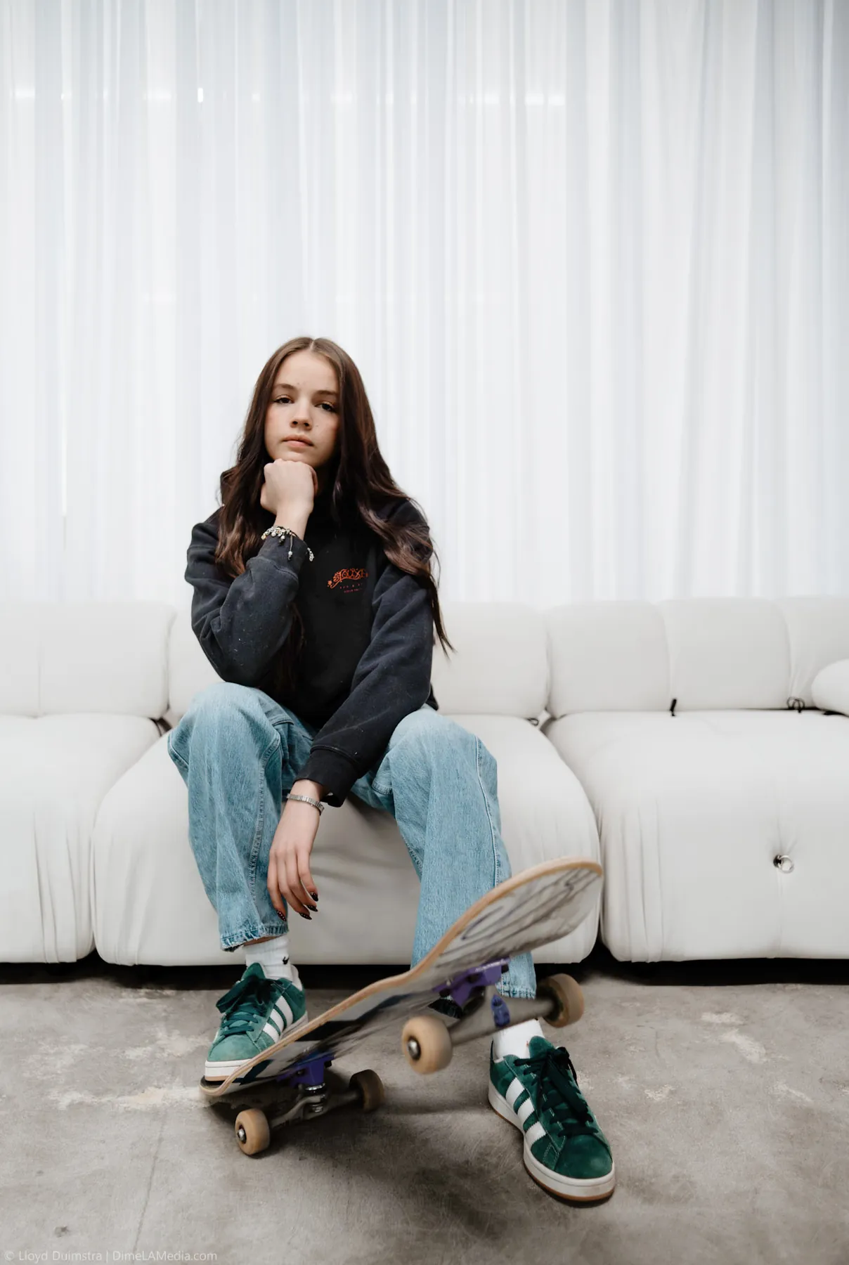 Branding portrait of a creative on a white couch with her skateboard