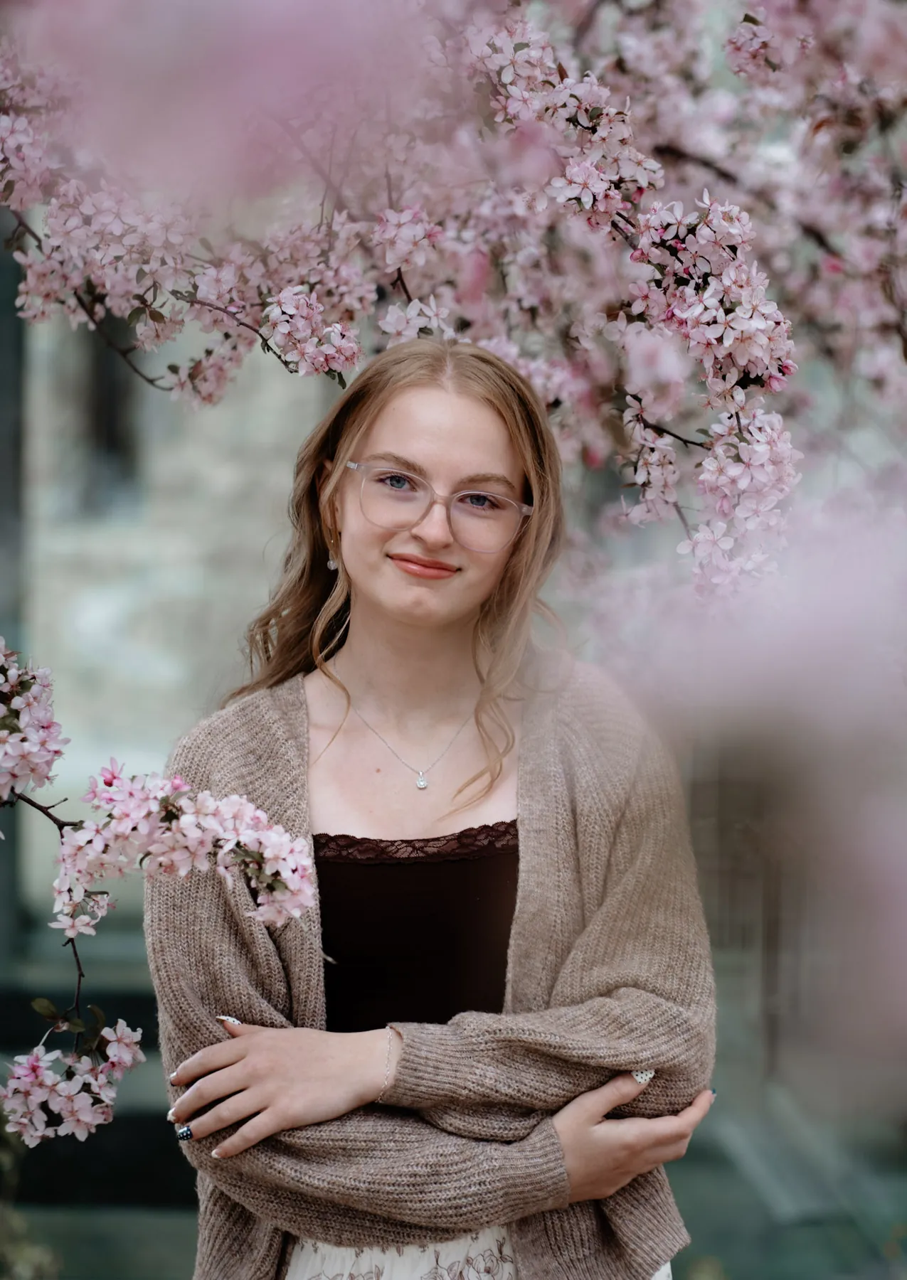 Syd Patzwald wrapped in a cardigan under pink spring blossoms