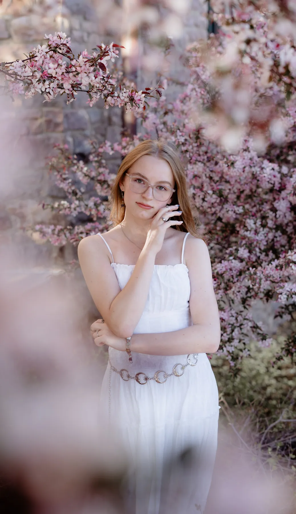 Syd Patzwald framed by pink crabapple blossoms, spring senior session