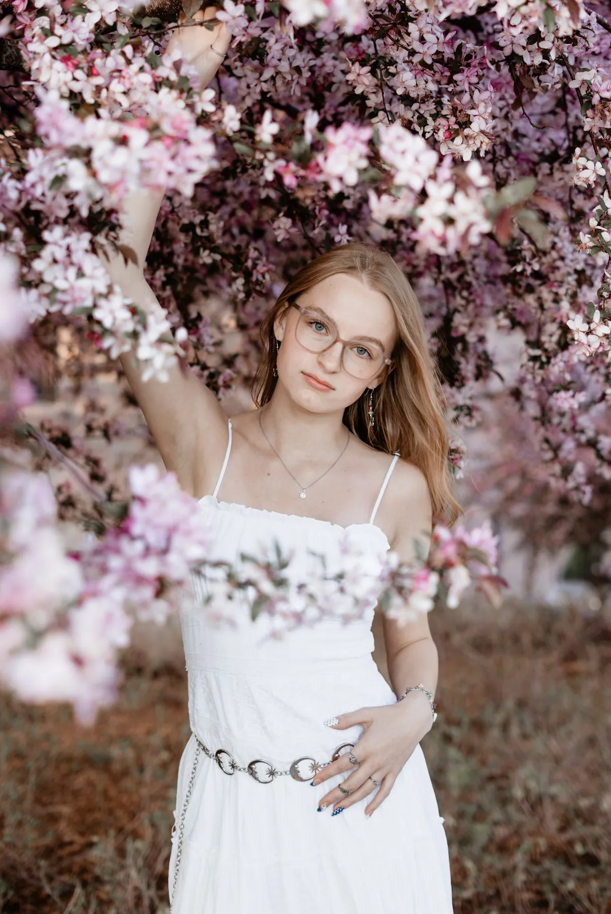 Syd Patzwald reaching into crabapple blossoms at her spring senior session