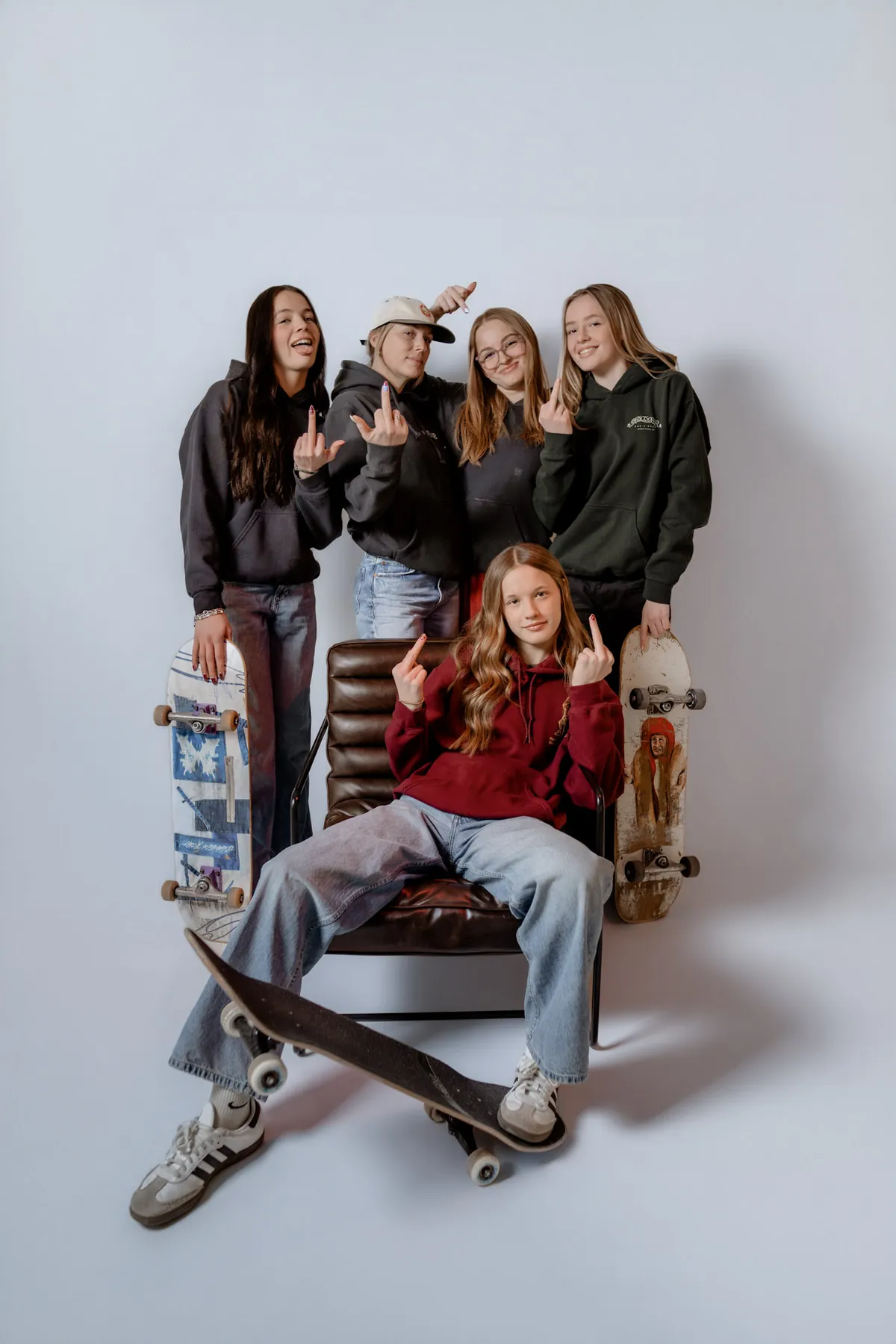 Syd Patzwald with her friend group and their skateboards in the studio
