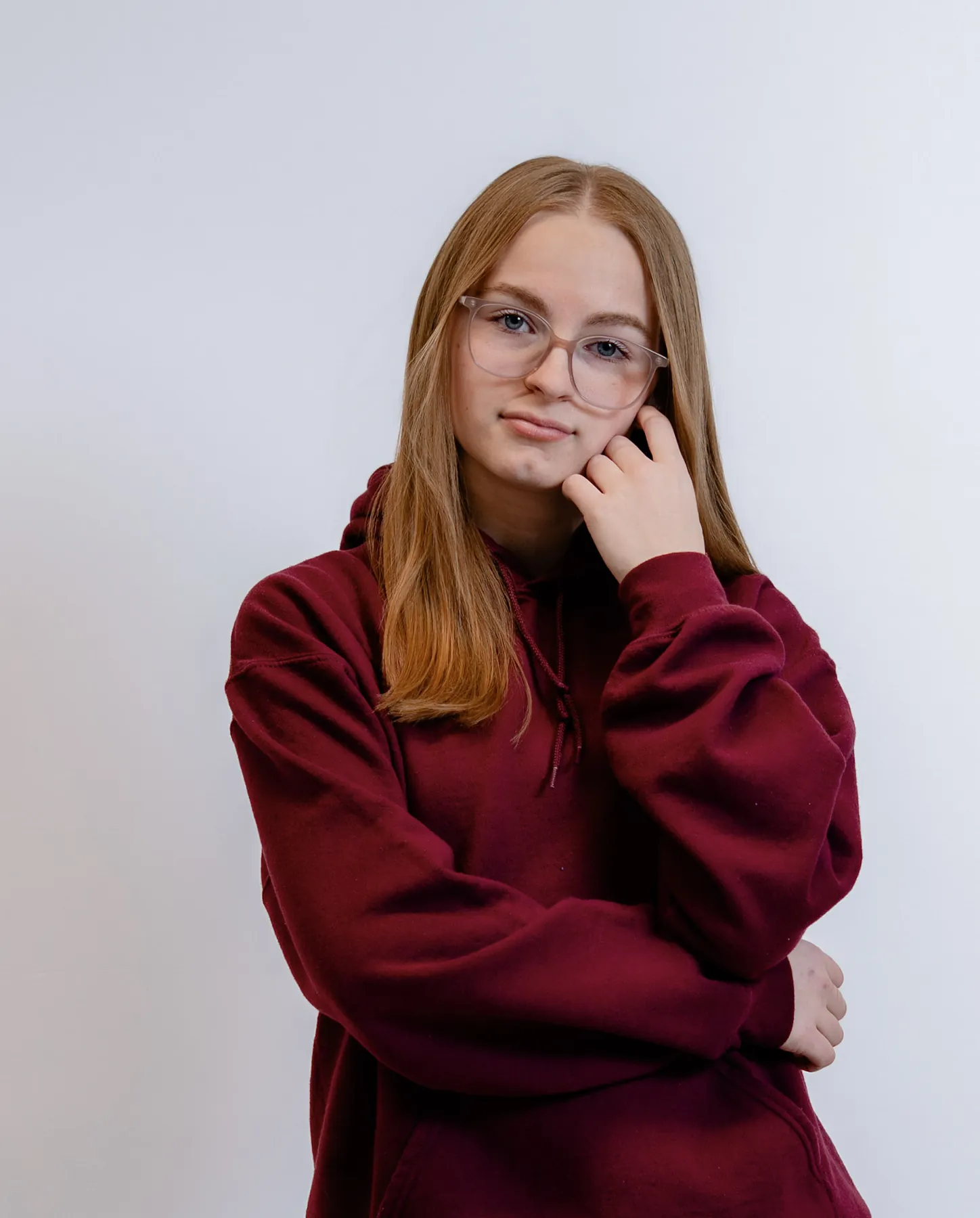 Studio portrait of Syd Patzwald in an oxblood hoodie