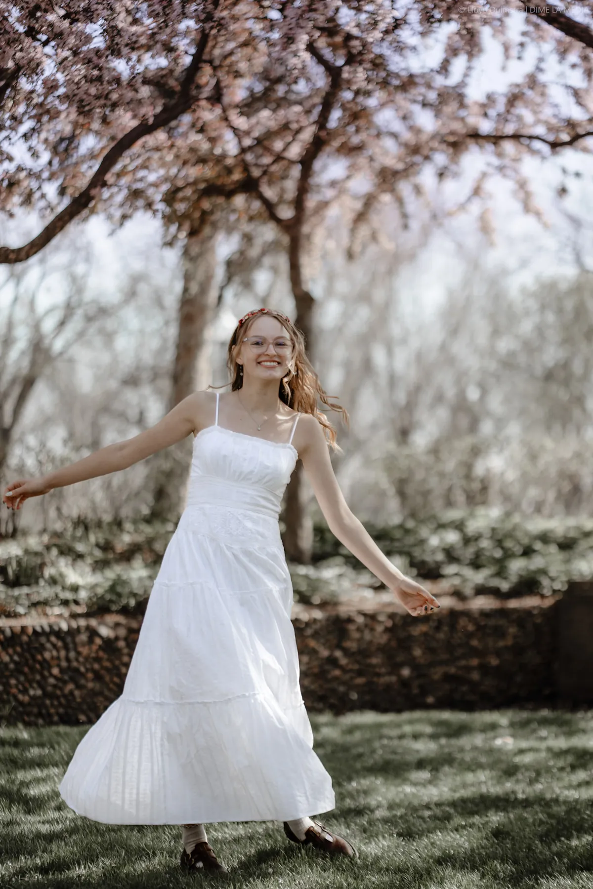 Syd Patzwald spinning in a white dress under a blossoming tree