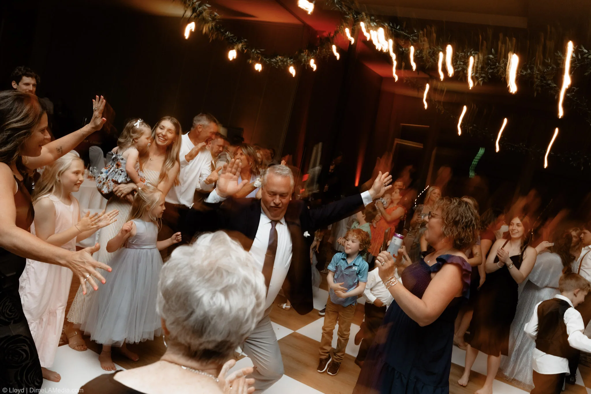 Guests dancing with their hands in the air as the light trails streak across the frame
