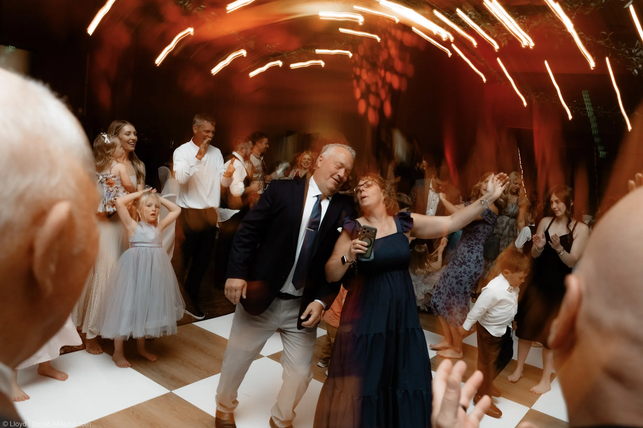 Father of the bride dancing in the middle of the floor as the reception lights blur around him