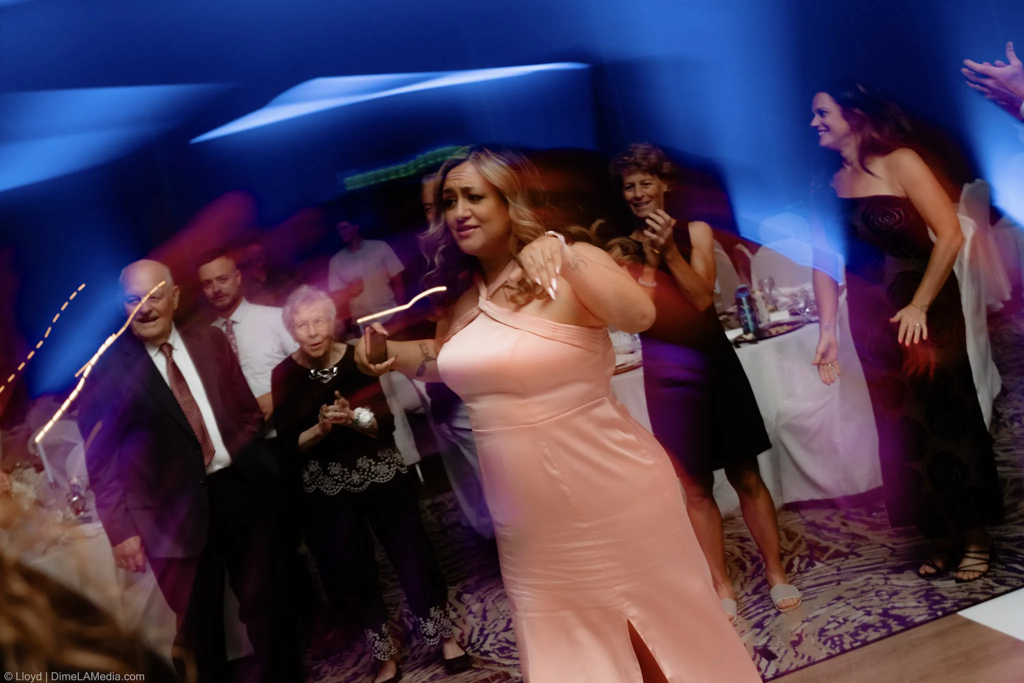 Bridesmaid dancing under blue and purple reception lighting