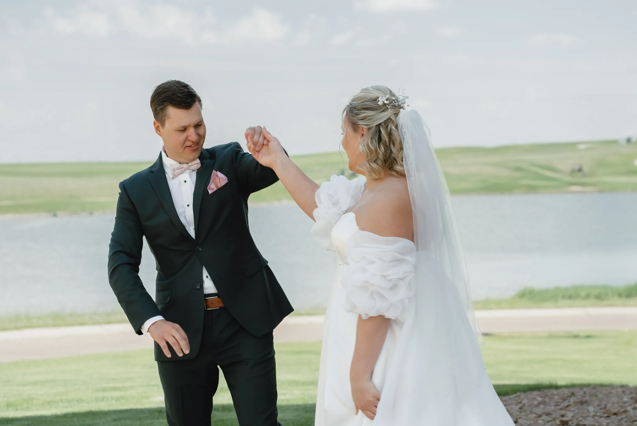 Groom spinning his bride under his arm on the lawn after the first look